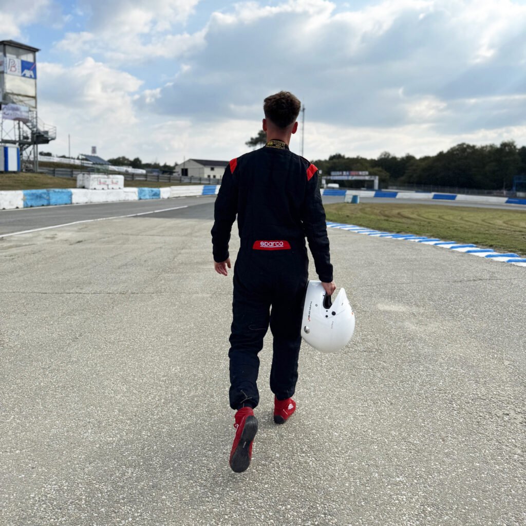 Pilote de course qui marche sur la piste, casque à la main